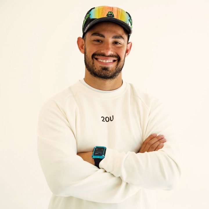 Ben Potzsch smiling with his arms crossed, wearing a cap and a white sweatshirt